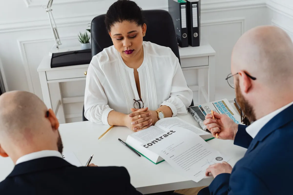 Jeune alternant en chemise discute avec son tuteur devant un ordinateur dans un open space lumineux